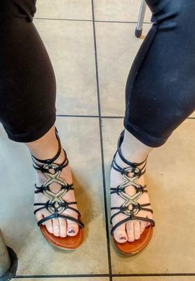 Ehefrau zeigt Füße in Sandalen für NL-Kommentare